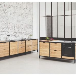 Isla de cocina minimalista con gabinetes de madera clara, encimera negra, horno empotrado y detalles metálicos, frente a pared de ladrillo blanco en ambiente moderno.