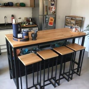 Mesa de cocina estilo industrial con tablero de madera clara y estructura metálica negra, acompañada de cuatro taburetes a juego. Ideal para desayunadores modernos.