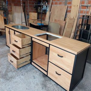 Mueble de cocina con estructura metálica negra y tablero de madera clara. Incluye fregadero circular y múltiples cajones abiertos, ideal para almacenamiento y funcionalidad.