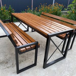 Juego de mesa y bancos de exterior con estructura de metal negro y superficies de madera pulida. Diseño moderno y resistente, ideal para jardines o terrazas.
