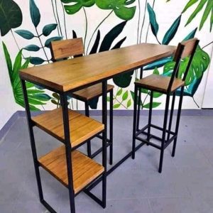 Mesa alta de madera con estructura de metal negro, acompañada de dos sillas a juego. Diseño moderno e industrial, adecuada para cocinas o bares pequeños.