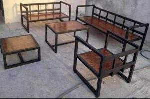 Juego de muebles de jardín con estructura de metal negro y tablones de madera. Incluye sofá, sillón y mesas de centro y lateral, ideal para exteriores. Diseño moderno y minimalista.