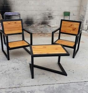 Conjunto de muebles de exterior: dos sillas y una mesa de centro con estructura negra y superficies de madera. Diseño moderno y minimalista ideal para terrazas y jardines.