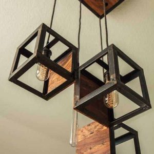 Lámpara de techo con diseño geométrico de metal y madera, forma de cubos colgantes con bombillas expuestas, estilo industrial moderno.