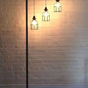 Una lámpara de pie moderna con estructura metálica negra, con tres luces colgantes de estilo industrial, ideal para iluminación interior elegante y contemporánea.