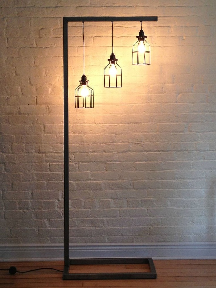 Una lámpara de pie moderna con estructura metálica negra, con tres luces colgantes de estilo industrial, ideal para iluminación interior elegante y contemporánea.