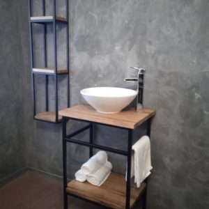 Lavabo de baño estilo industrial con estructura de metal negro y superficies de madera. Incluye una repisa inferior para almacenamiento y un toallero lateral. Elegante y funcional.