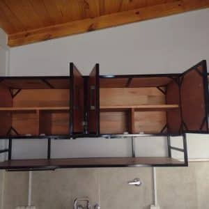 Armario de cocina flotante en madera, con estructura metálica negra. Cuenta con puertas abiertas y estantes internos para almacenamiento. Diseño contemporáneo.
