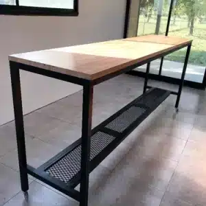 Mesa alta rectangular con estructura metálica negra y superficie de madera clara. Incluye una repisa inferior de malla. Ideal para cocina o taller. Diseño moderno y funcional.