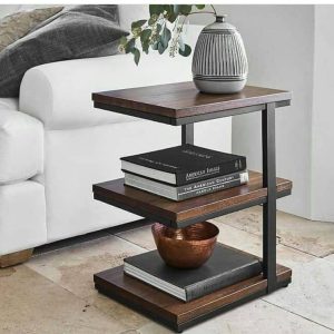 Mesa auxiliar moderna de madera oscura y metal, con tres niveles; sostiene libros y una maceta decorativa en su parte superior. Ideal para sala de estar contemporánea.