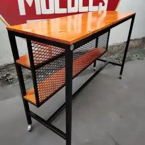 Mesa alta de estilo industrial con estructura de metal negro, superficie y estantes de madera, y ruedas para fácil movilidad. Ideal para cocina o bar.