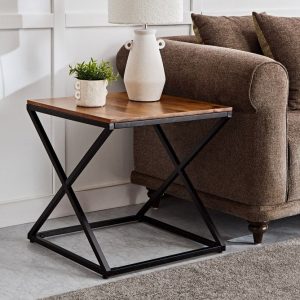 Mesa auxiliar elegante con estructura de metal negro en forma de X y superficie de madera. Ideal para decoraciones modernas o industriales, situada junto a un sofá marrón.