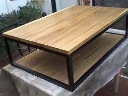 Mesa de centro rectangular con estructura de metal negro y tablero de madera. La parte inferior también incorpora una repisa de madera, ideal para almacenamiento adicional.