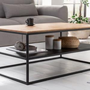 Mesa de centro moderna con superficie de madera clara y estructura de metal negro. Incluye un estante inferior para almacenamiento. Diseño minimalista y funcional.