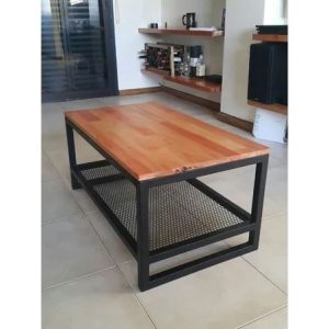 Mesa de centro rectangular con superficie de madera clara, marco de metal negro, y un estante inferior de rejilla de metal en un ambiente moderno.