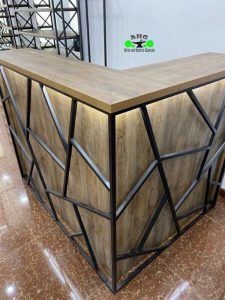 Mostrador en forma de L con top de madera y estructura metálica con diseño geométrico. Ideal para recepciones o mostradores de atención.