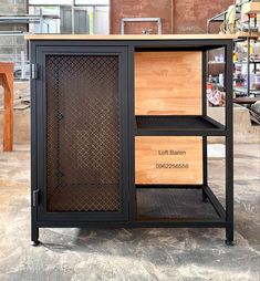 Gabinete de estilo industrial con estructura metálica negra, puerta de malla y estantes de madera clara. Ideal para almacenamiento en espacios modernos o rústicos.