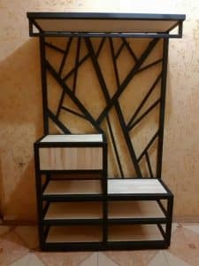 Estantería moderna con estructura de metal negro y diseño geométrico asimétrico. Cuenta con múltiples estantes de madera clara para almacenamiento o decoración. Ideal para espacios contemporáneos.