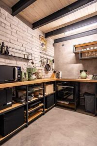 Mueble de cocina en esquina con estantes abiertos de madera y metal, almacenando electrodomésticos y utensilios. Diseño moderno con acabados industriales.