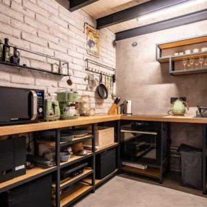 Mueble de cocina en esquina con estantes abiertos de madera y metal, almacenando electrodomésticos y utensilios. Diseño moderno con acabados industriales.