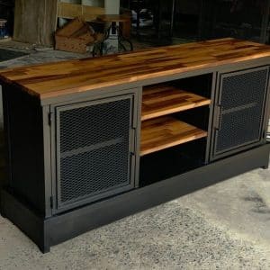 Mueble de estilo industrial con estructura negra y puertas de rejilla metálica, acompañado de una resistente tapa de madera y estantes abiertos al centro. Ideal para almacenaje.