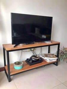 Mueble de TV con diseño minimalista, estructura de metal negro y dos niveles de madera. Incluye espacio para decoraciones y almacenamiento.