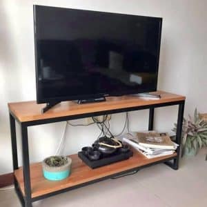 Mueble de TV con diseño minimalista, estructura de metal negro y dos niveles de madera. Incluye espacio para decoraciones y almacenamiento.