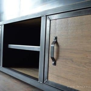 Mueble de almacenamiento estilo industrial con marco de metal negro y puertas de madera. Incluye manijas metálicas y un compartimento abierto central con estante. Ideal para salas de estar.