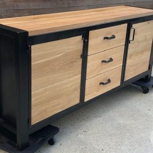 Mueble alacena de estilo industrial con marco negro, tres cajones y dos puertas de madera clara. Diseño moderno y funcional sobre bases con ruedas.