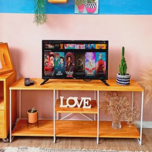 Mueble de TV moderno con estantes de madera clara y patas de metal blanco, decorado con cáctus y letras 'LOVE' en la repisa central.