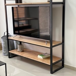 Centro de entretenimiento moderno con estructura de metal negro y estantes de madera clara, sostiene un televisor y tiene espacio para decoración y libros.
