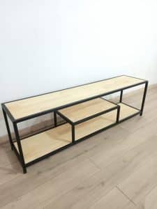 Banco de madera clara con estructura metálica negra. Diseño minimalista con tres niveles para almacenamiento. Ideal para salas modernas o industriales.