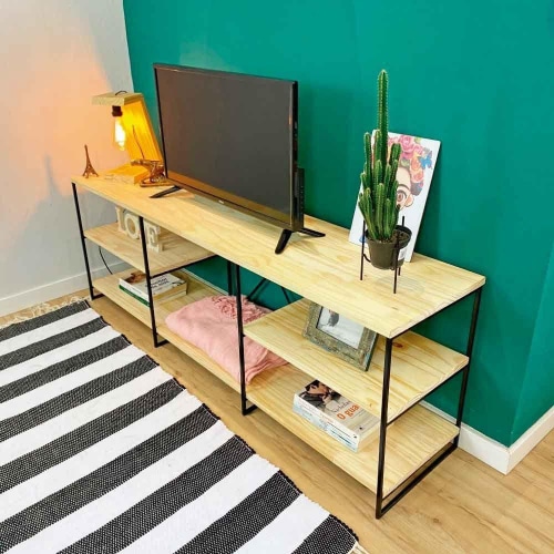 Mueble estante de madera claro con estructura de metal negro en sala moderna. Incluye tres niveles para soporte de televisión, decoración y almacenamiento. Diseño minimalista y funcional.