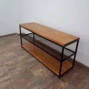 Mesa de consola de madera con estructura metálica negra, dos niveles de estantes perforados, diseño moderno y minimalista, ubicada en una habitación con suelo de baldosas marrones.