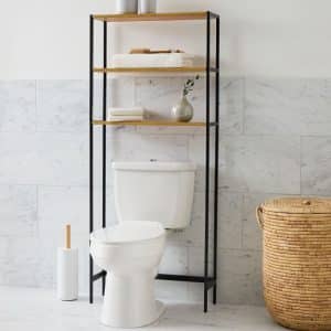 Estantería de baño con estructura metálica negra y tres repisas de madera clara, situada sobre el inodoro. Ideal para almacenamiento en espacios pequeños y decoración moderna.