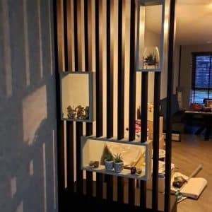 Divisor de ambiente de listones verticales de madera oscura, con nichos enmarcados para decoración, ideal para modernizar y delimitar espacios interiores con estilo contemporáneo.