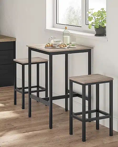 Conjunto de mesa alta y dos taburetes con estructura de metal negro y superficie de madera clara, ideal para cocinas pequeñas o espacios modernos y minimalistas.