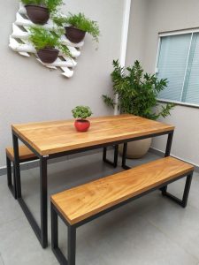 Mesa y bancos de madera con base de metal negro, estilo industrial. Diseño minimalista ideal para exteriores, colocados sobre azulejos grises.