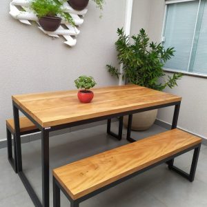 Mesa y bancos de madera con base de metal negro, estilo industrial. Diseño minimalista ideal para exteriores, colocados sobre azulejos grises.