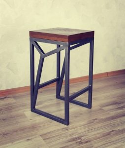 Taburete moderno con un asiento de madera cuadrado y base de metal negro con diseño geométrico. Ideal para decoración contemporánea o industrial.